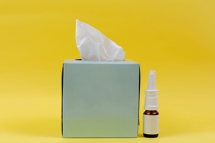 picture of a tissue and a hayfever spray on a yellow background 