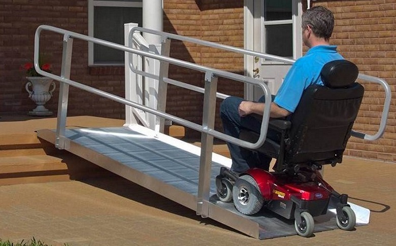 Man in wheelchair on ramp in front of a house